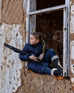 Foto de una niña ucraniana de 9 años con un chupetín en la boca y un rifle en la mano